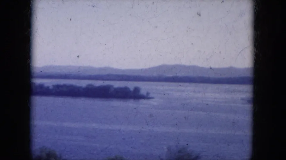 1969 Lake Canyon, Arizona home-movie frame with broad water, low hills, a distant tree line, and visible 8mm gate borders.