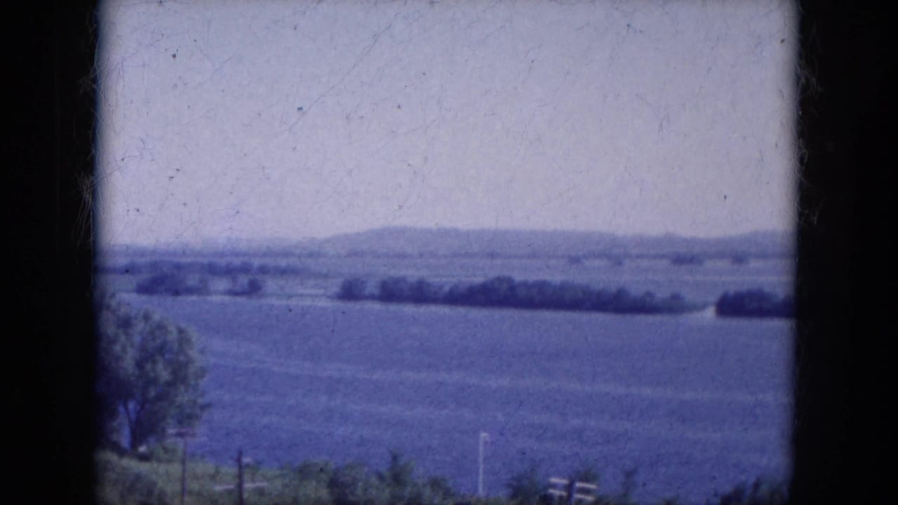 Distant open landscape seen through a dark 8mm film frame edge.