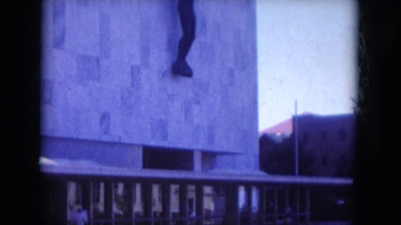 Modernist building in Lake Canyon, Arizona, filmed in 1969 with a dark human-form sculpture mounted high on the stone facade.