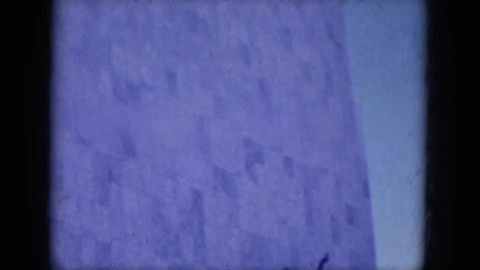 1969 8mm frame from the Lake Canyon, Arizona metadata context showing a close, blue-tinted view of pale exterior panels and heavy frame shadow.