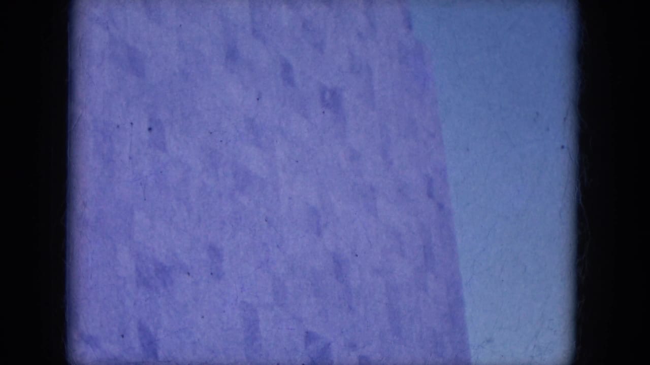 Mostly blue-tinted film leader or obscured frame with dark film borders.