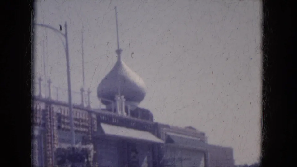 Soft 1969 Lake Canyon 8mm frame showing the domed roadside building, utility poles, pale sky, and edge-darkened film border.