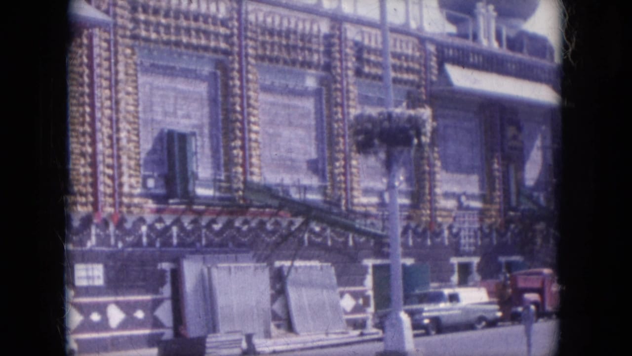 The camera frames the ornate facade in Lake Canyon, Arizona, with parked late-1960s cars and small street details near the building front.
