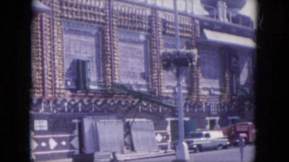 The camera frames the ornate facade in Lake Canyon, Arizona, with parked late-1960s cars and small street details near the building front.