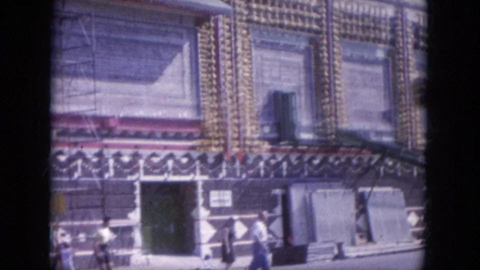 A closer street-level view shows the decorated building front, dark doorway, shuttered windows, and small people near the sidewalk in 1969 Arizona footage.