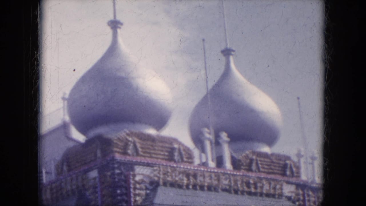Upper portion of a decorated building with large onion-shaped domes and patterned trim.
