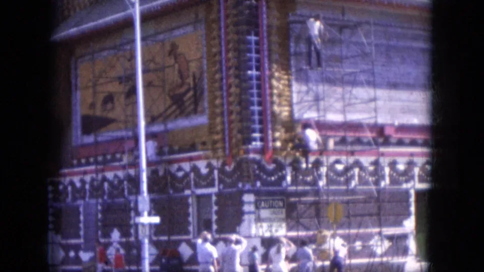 1969 Lake Canyon frame showing a broader exterior view of the ornate domed building, with scaffolding, workers, pedestrians, and street signage.