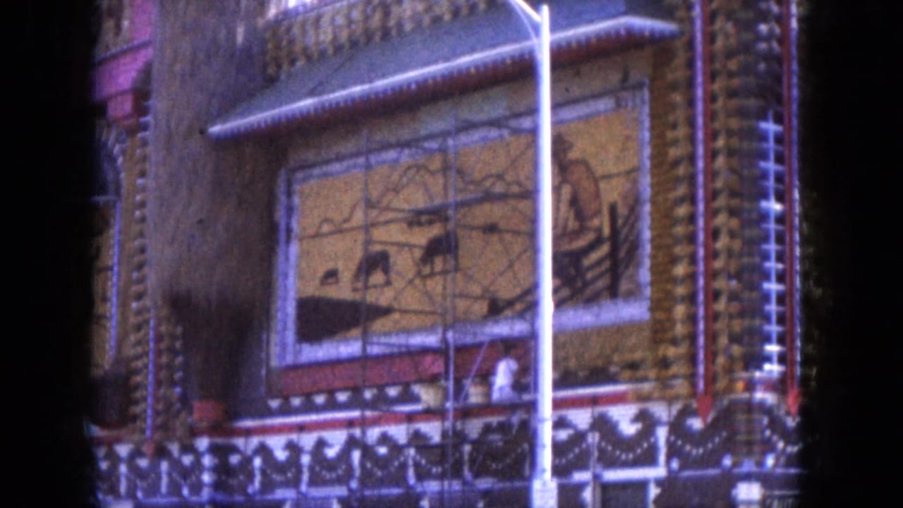 Ornate facade with painted mural panels, arched trim, streetlight, and dark frame edges.