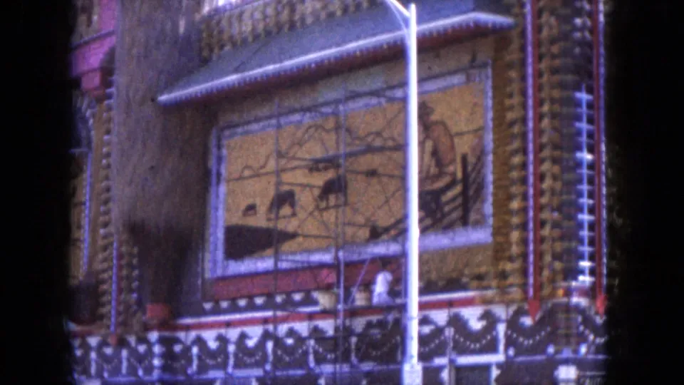 1969 Lake Canyon, Arizona 8mm frame showing a colorful exterior facade with mural panels, decorative trim, and a streetlight in front.