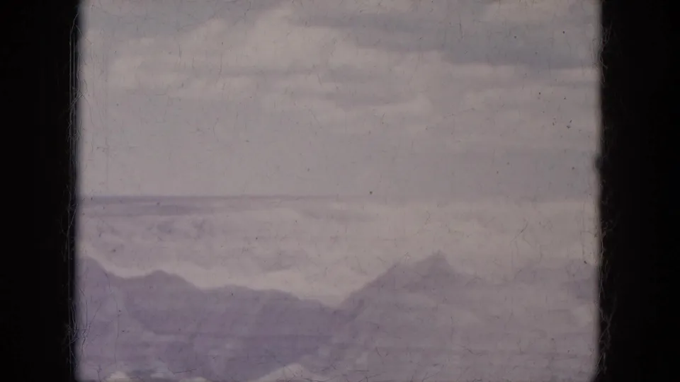 1969 Arizona home-movie frame with distant mountain silhouettes below layered clouds and soft 8mm fading.