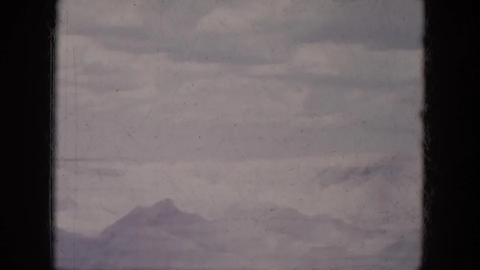 Lake Canyon 8mm frame showing a soft distant mountain range under cloudy sky with visible archival film wear.