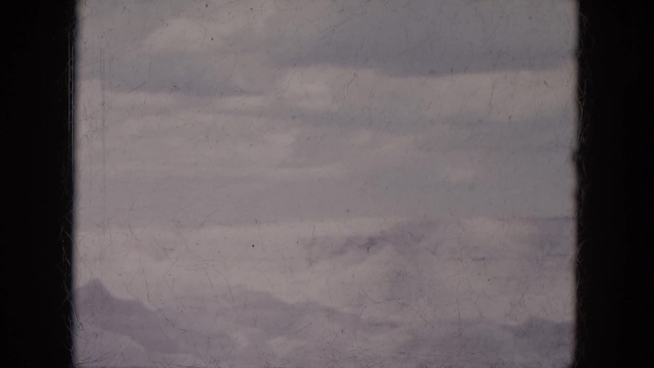 Hazy distant ridges beneath a pale sky with dark film-edge shadowing.