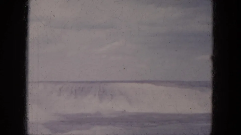 1969 Lake Canyon, Arizona home-movie still showing a dark lower band, hazy horizon, and muted desert slope.