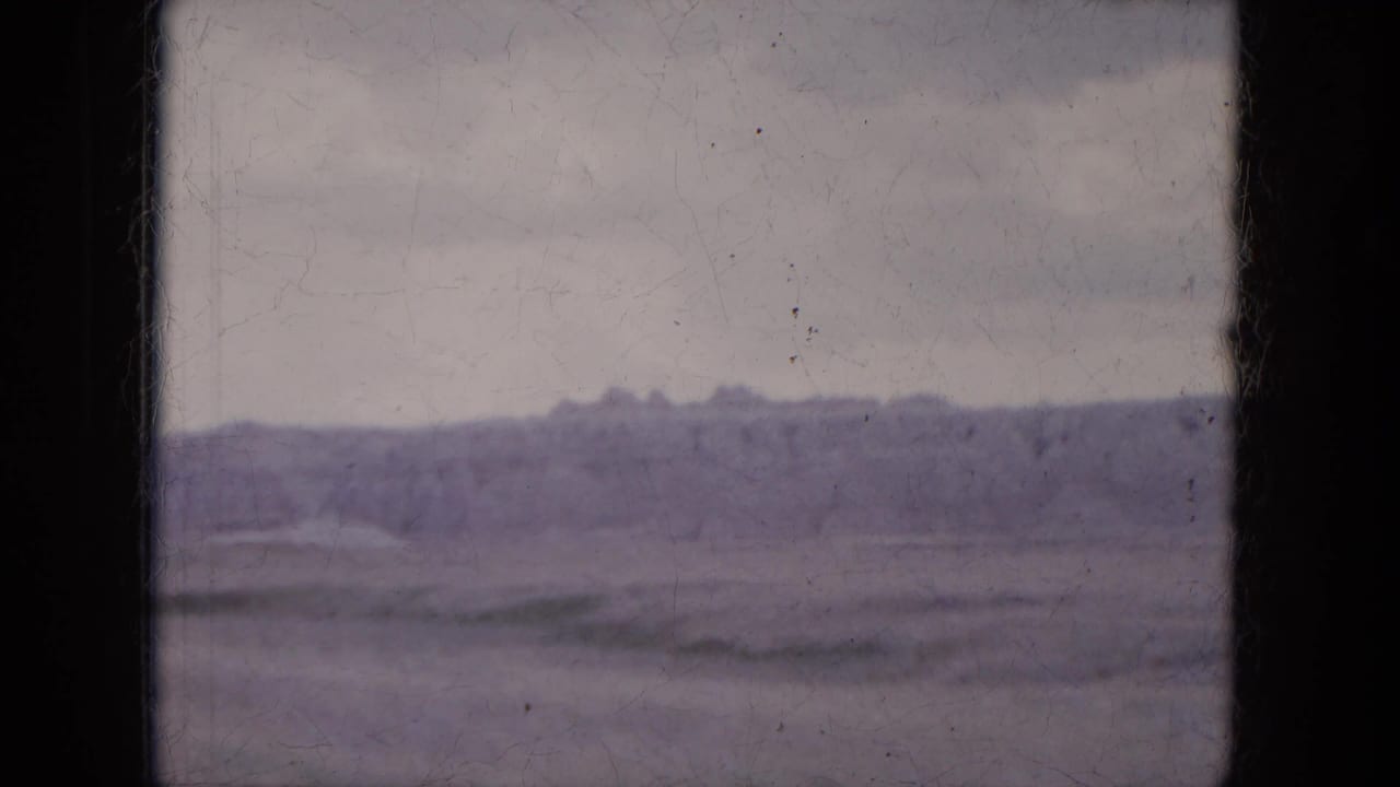 Soft, grainy view of a distant eroded ridge under a pale sky.