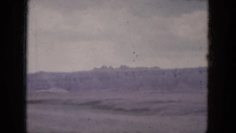 1969 8mm frame from Lake Canyon, Arizona, showing a low eroded ridge and open desert terrain beneath a muted sky.