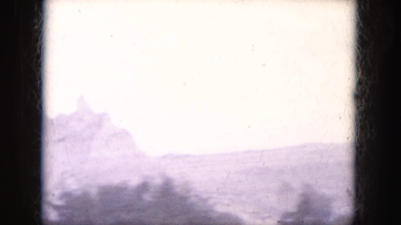 Overexposed hazy desert rock shapes seen through a dark film or window border.