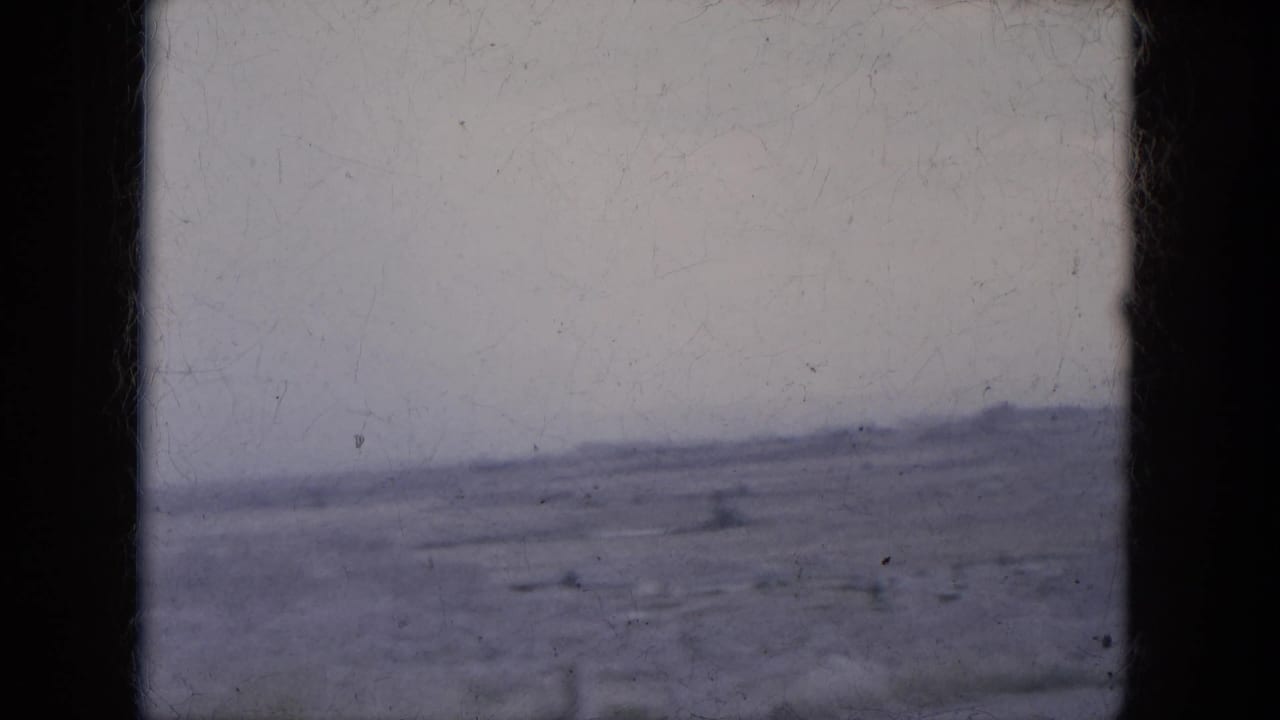 1969 8mm Lake Canyon, Arizona footage showing a distant low ridge and broad desert plain from a moving vehicle perspective.