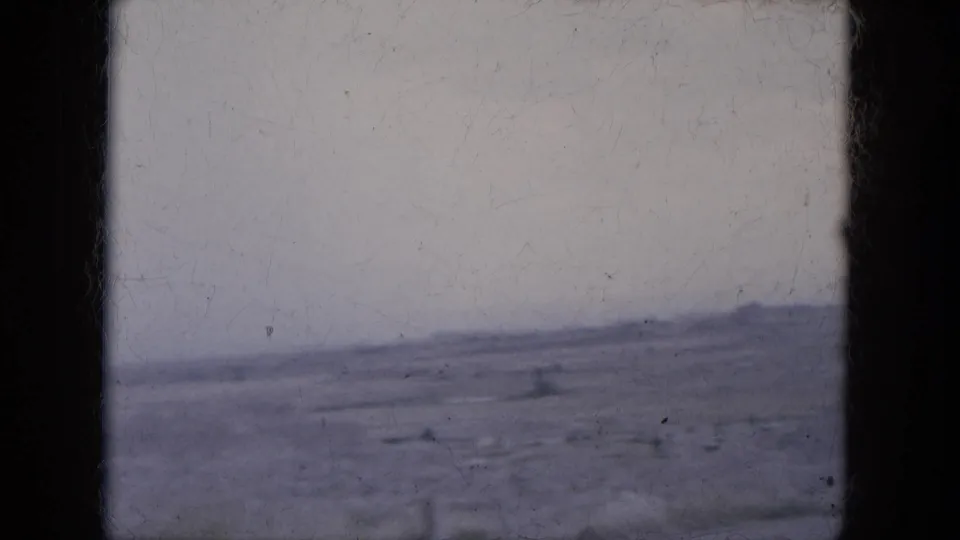 1969 8mm Lake Canyon, Arizona footage showing a distant low ridge and broad desert plain from a moving vehicle perspective.