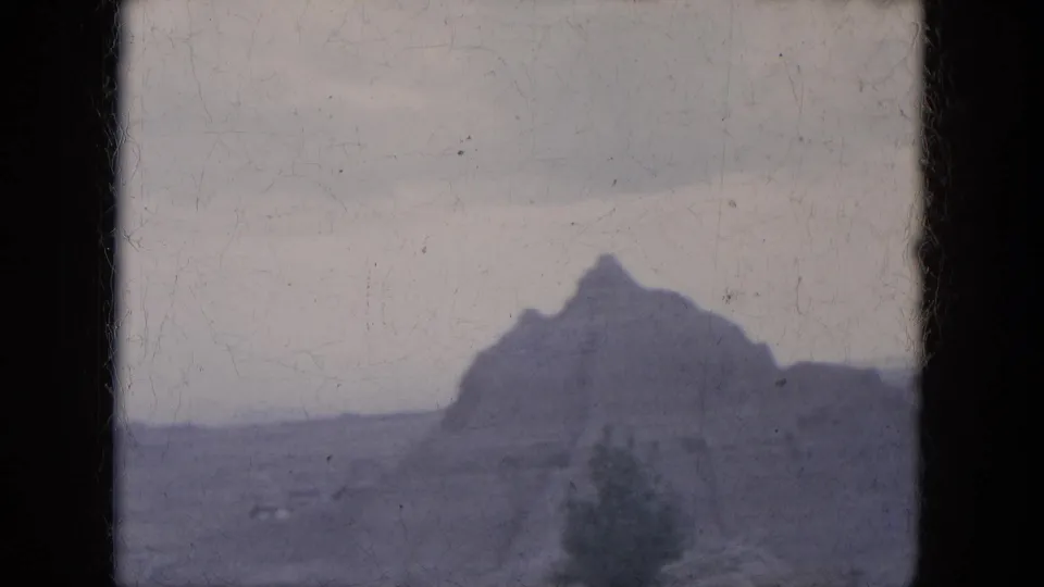 1969 8mm Lake Canyon, Arizona home-movie frame with a distant rock formation, desert scrub, and soft faded color.