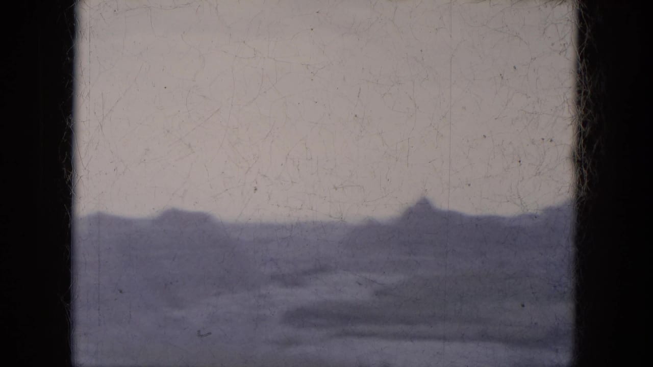 Soft purple-tinted view of distant desert ridges beneath a pale sky.