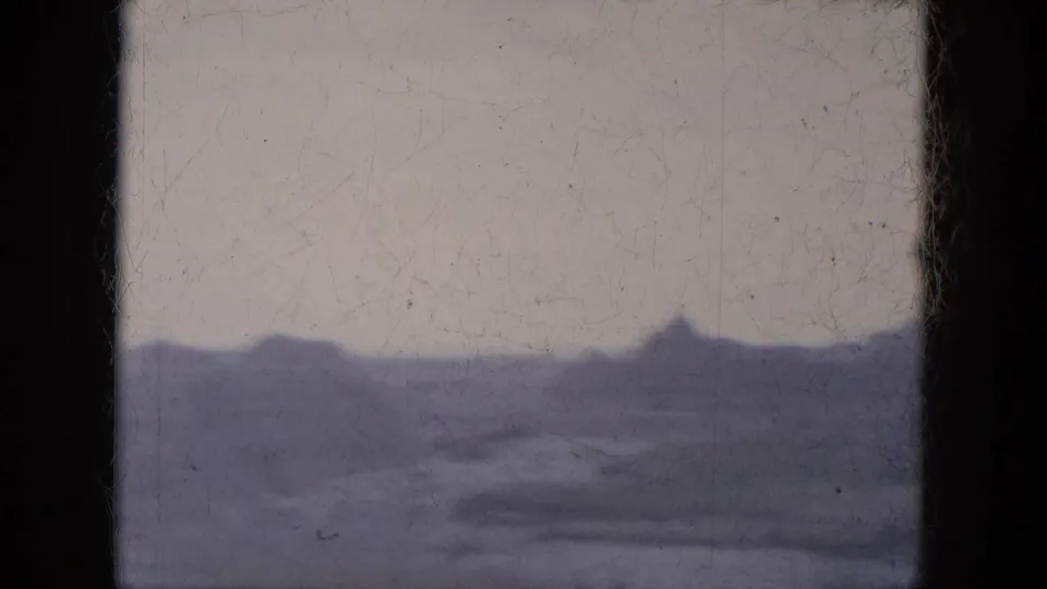 1969 8mm home-movie frame from Lake Canyon, Arizona, showing distant canyon ridges through a dark film-frame edge.