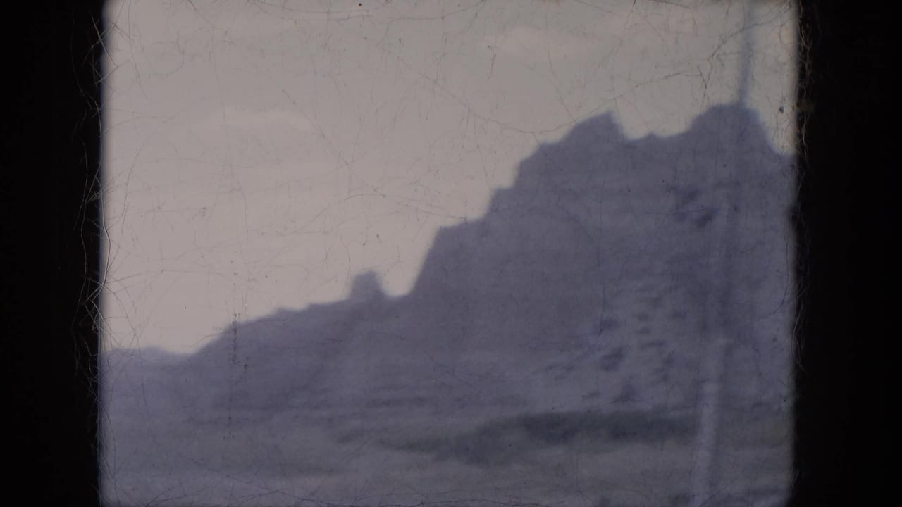 1969 Lake Canyon, Arizona frame with a jagged canyon wall and muted desert foreground on aged 8mm film.