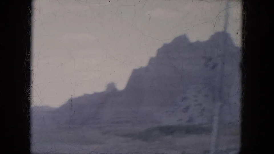 1969 Lake Canyon, Arizona frame with a jagged canyon wall and muted desert foreground on aged 8mm film.