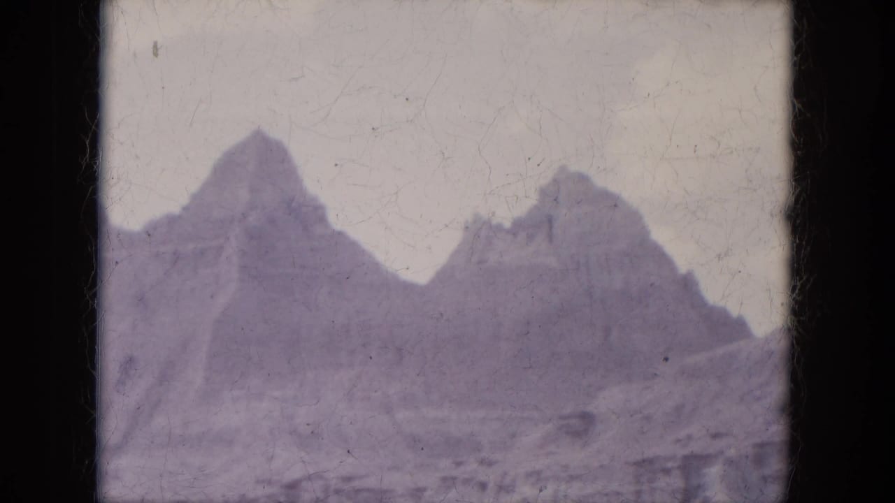 Jagged canyon peaks under a pale sky with dark 8mm frame edges.