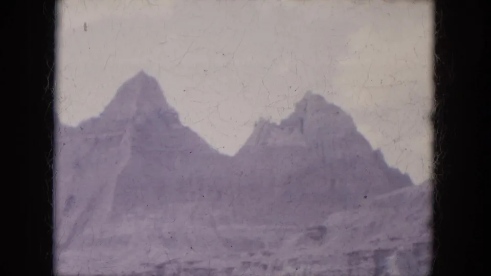 1969 8mm home-movie view of rugged Lake Canyon, Arizona rock peaks seen from below under a pale sky.