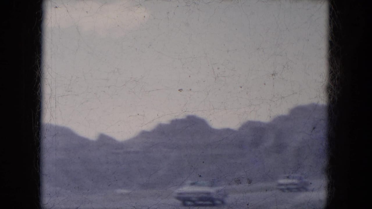 Rocky canyon ridge with small distant automobiles near the lower edge.