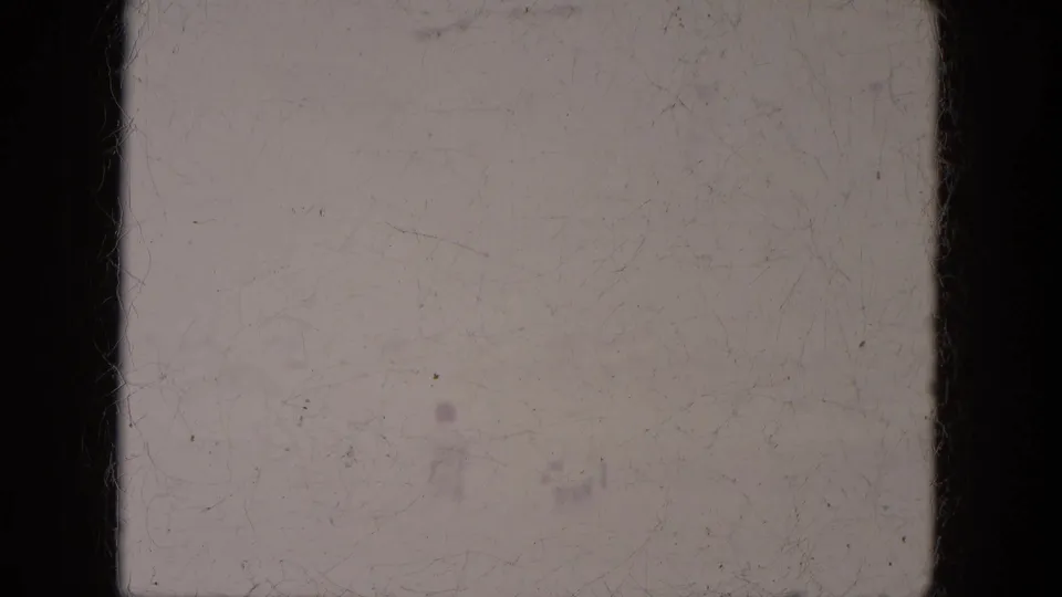 A faded 1969 home-movie frame showing a faint person against pale outdoor ground at Lake Canyon.