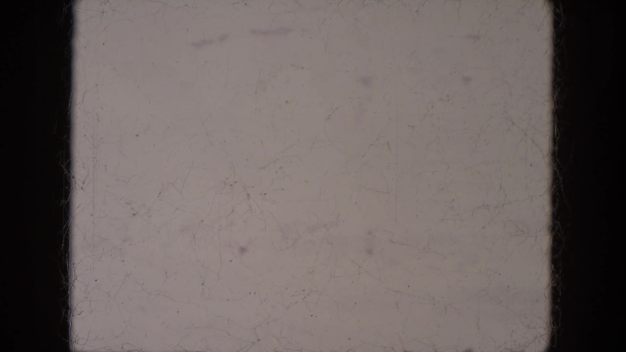Blank 1969 Lake Canyon 8mm frame with pale exposure, dark side borders, faint vertical lines, dust, and surface marks.