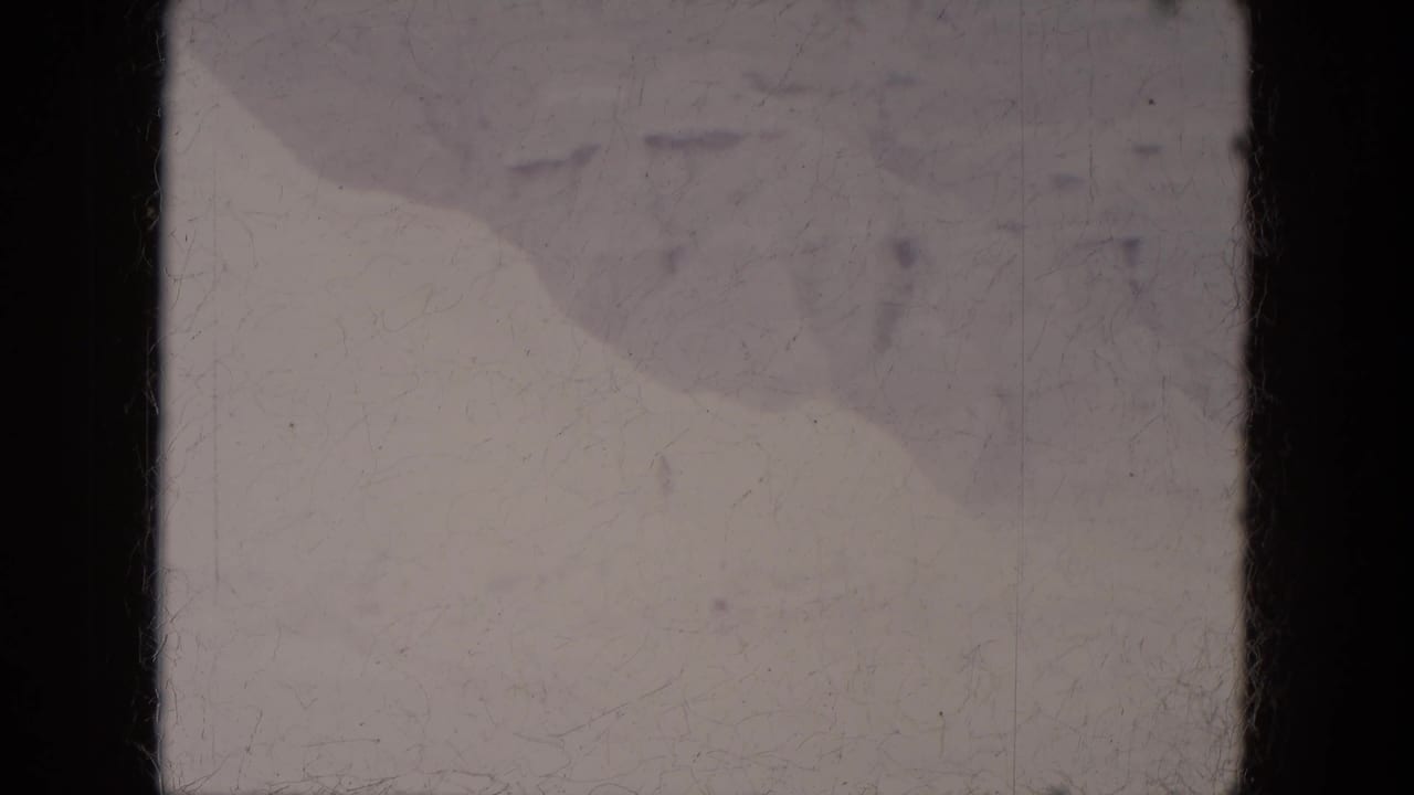Snow-covered ground with soft mounds and dark 8mm film borders.