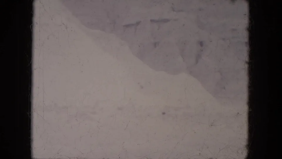 1969 Lake Canyon, Arizona 8mm frame showing a faded snowy landscape with indistinct distant shapes and heavy film-edge darkness.