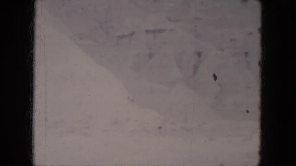 1969 Lake Canyon, Arizona 8mm frame showing a dim, faded snowy surface with indistinct marks and a small dark speck near center.