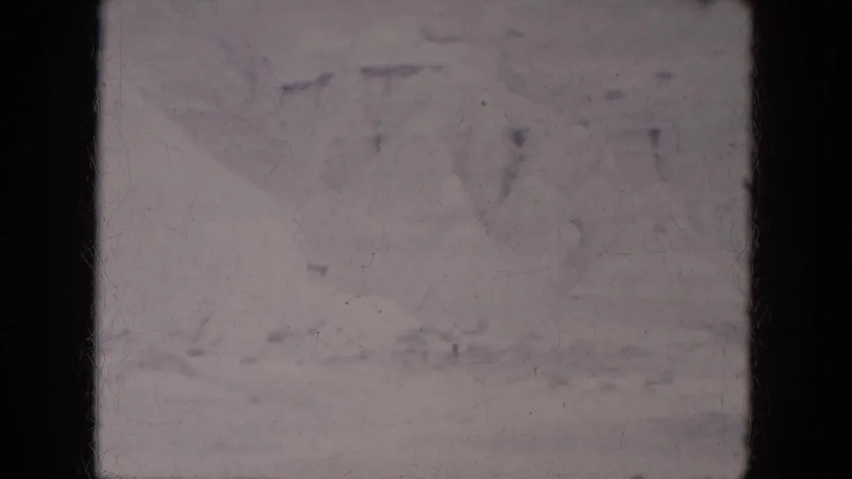 1969 8mm frame from Lake Canyon, Arizona, showing a washed, distant snowy mountain view beneath a pale sky.