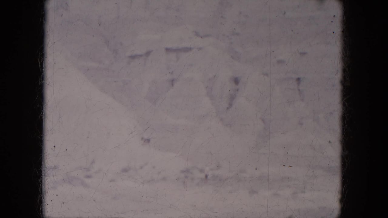 Washed mountain scene with pale sky, faint ridges, and visible film wear.