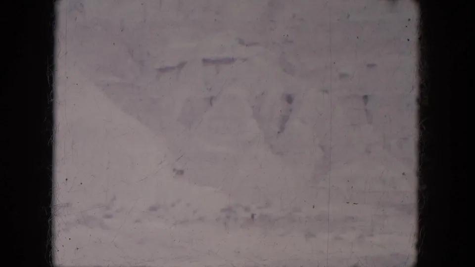 1969 Lake Canyon 8mm frame with faint snow-dusted ridges, pale sky, surface marks, and dark frame borders.