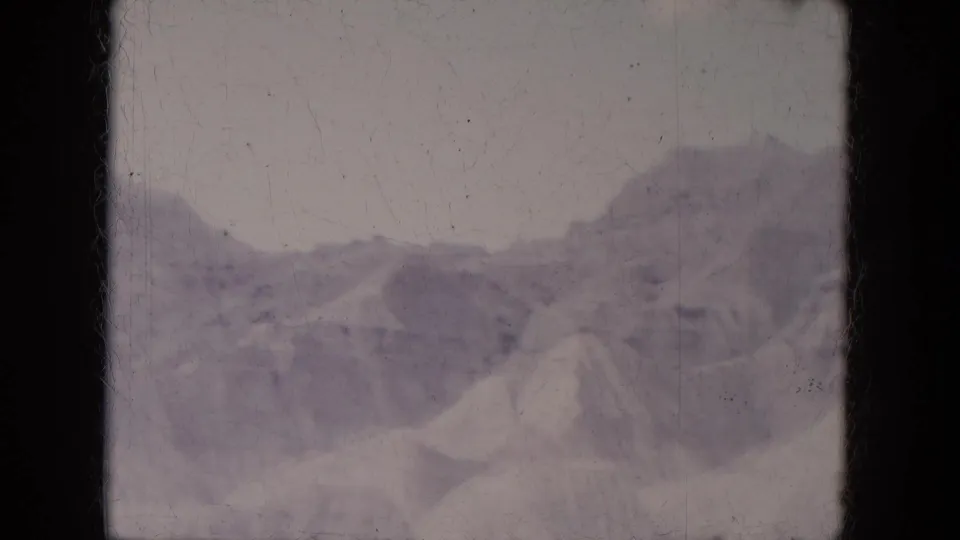 1969 8mm home-movie frame of a distant snowy ridge and steep pale slopes in Lake Canyon, Arizona.