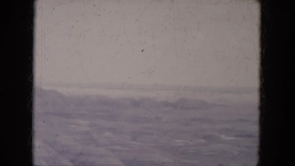 Soft 1969 8mm landscape frame showing pale open ground and distant canyon hills in Arizona.