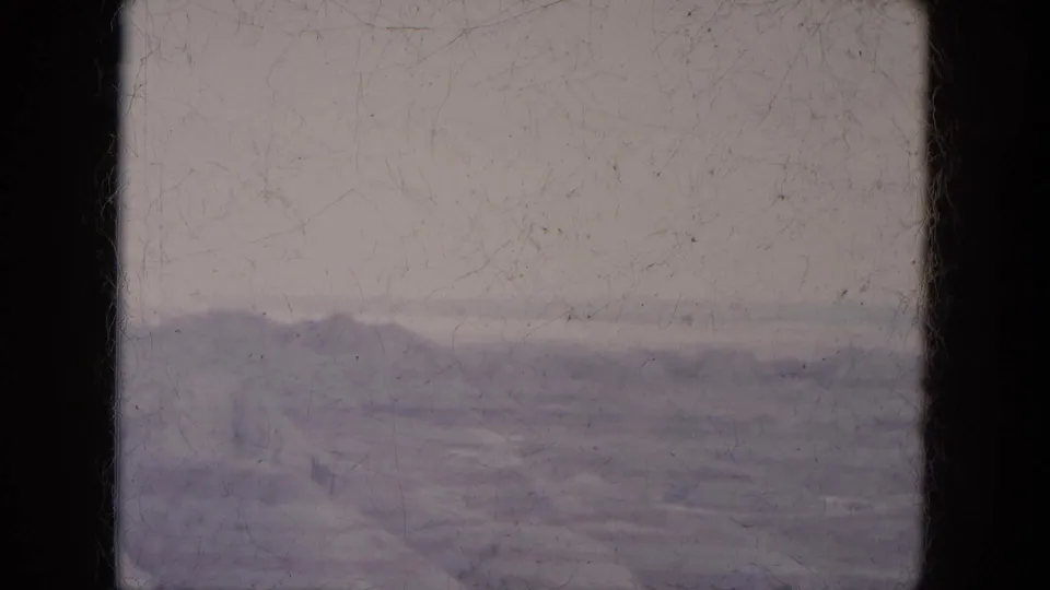 Lake Canyon, Arizona home-movie frame with distant hills, pale foreground, and visible 8mm grain and wear.