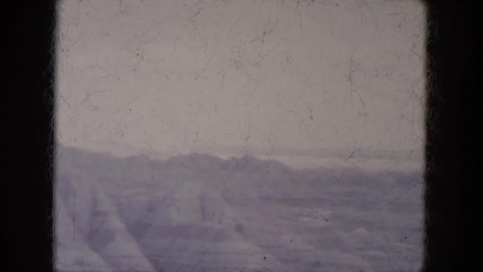 1969 Lake Canyon, Arizona home-movie frame showing distant rocky hills beneath a pale sky with visible 8mm border and dust.