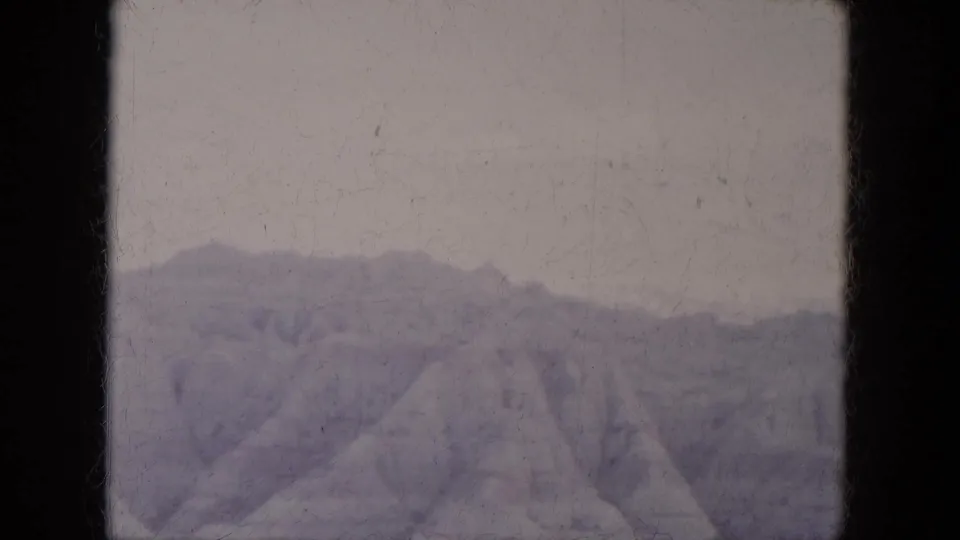 Faded 1969 8mm home-movie frame of Lake Canyon rocky slopes with distant ridges and no visible people or structures.