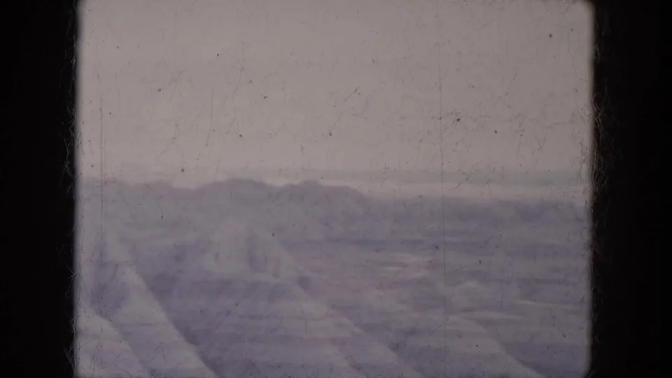 1969 Lake Canyon, Arizona frame with distant desert hills, a low ridgeline, pale sky, and visible 8mm dust and scratches.