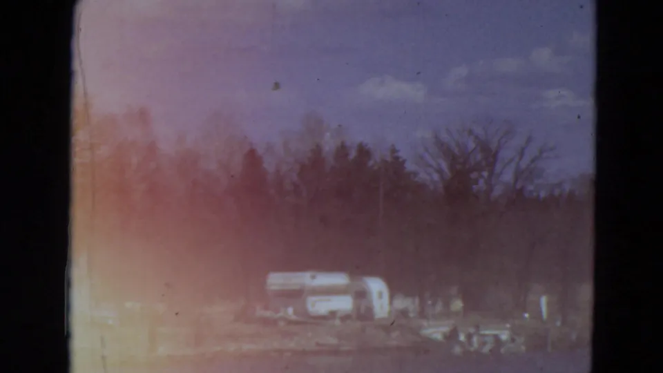 Faded 1969 Minnesota 8mm frame showing campers or trailers near a tree-lined lakeside area with strong red and blue color shifts.