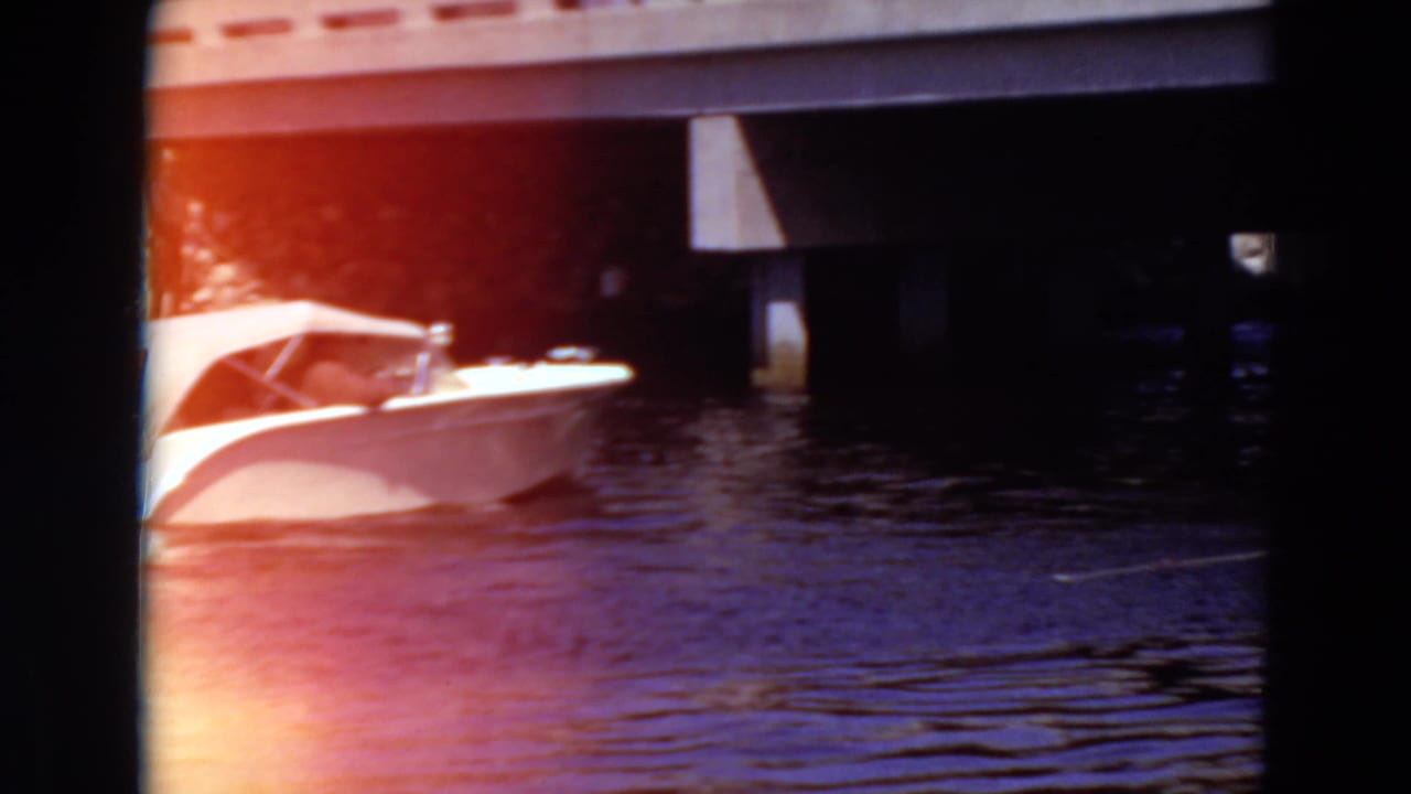 White speedboat partly visible on lake water beside a concrete bridge.