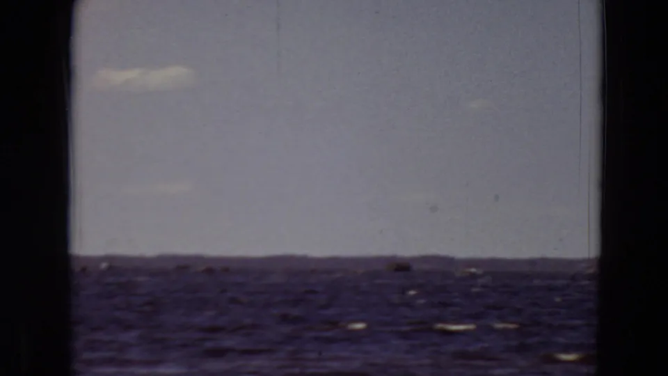 1969 Minnesota 8mm frame of open water with faint whitecaps, distant horizon, pale sky, and dark film-window edges.