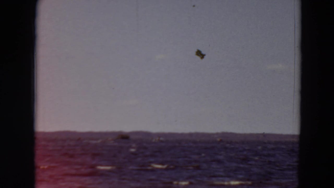 Choppy water with small whitecaps below a pale sky and distant low shoreline.