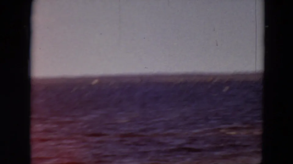 1969 Minnesota 8mm view of wind-ruffled water beneath a pale sky, with dark frame edges and a distant shoreline.