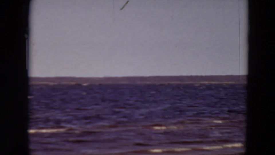 1969 Minnesota 8mm closing frame showing rough water, a long distant shoreline, and visible home-movie frame borders.